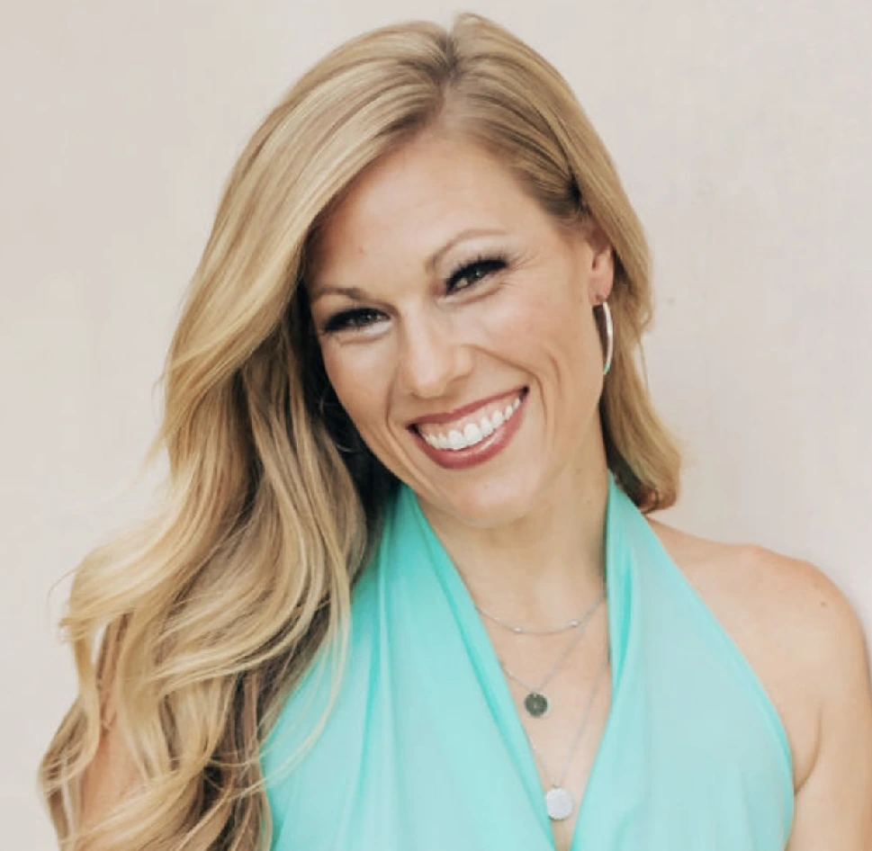 A woman in a blue top smiling for the camera.