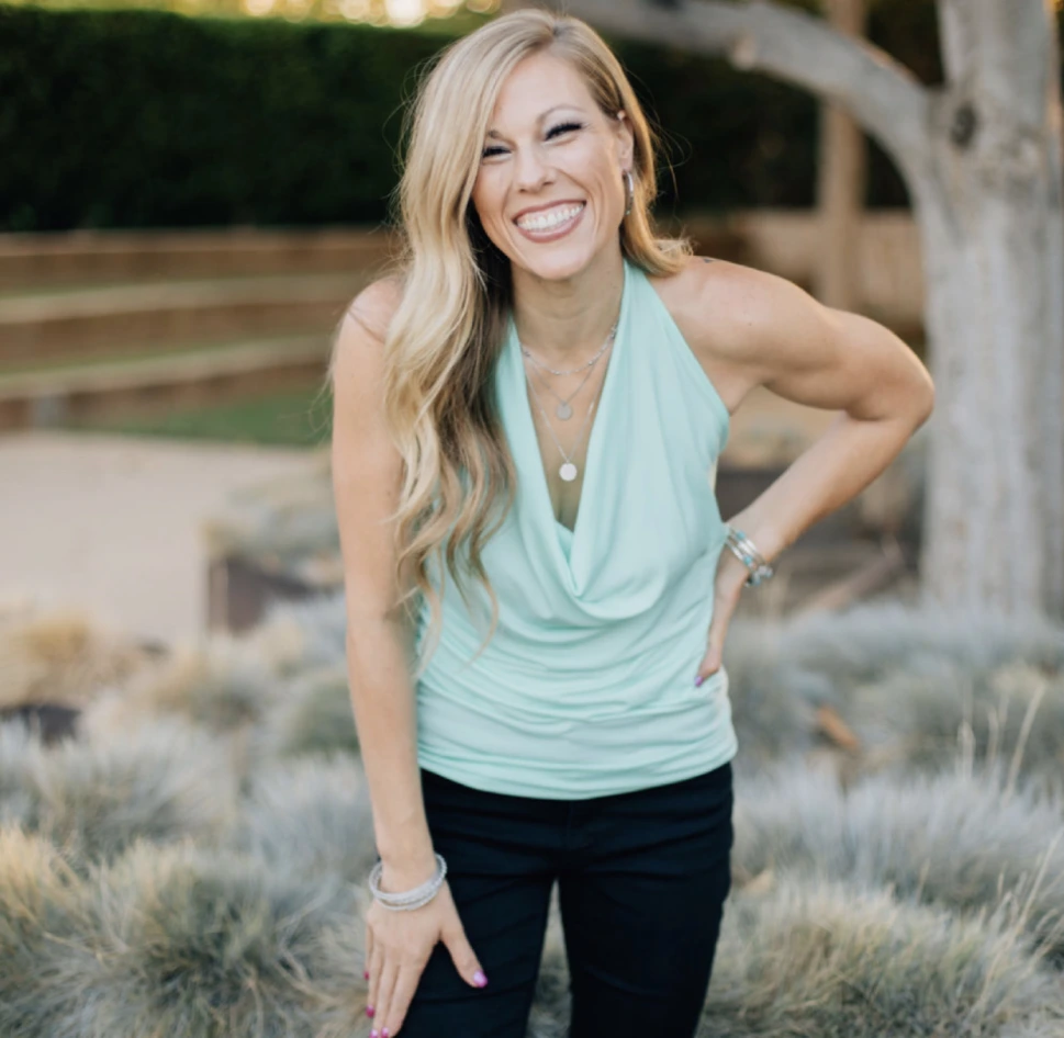 A woman standing in the grass with her hands on her hips.